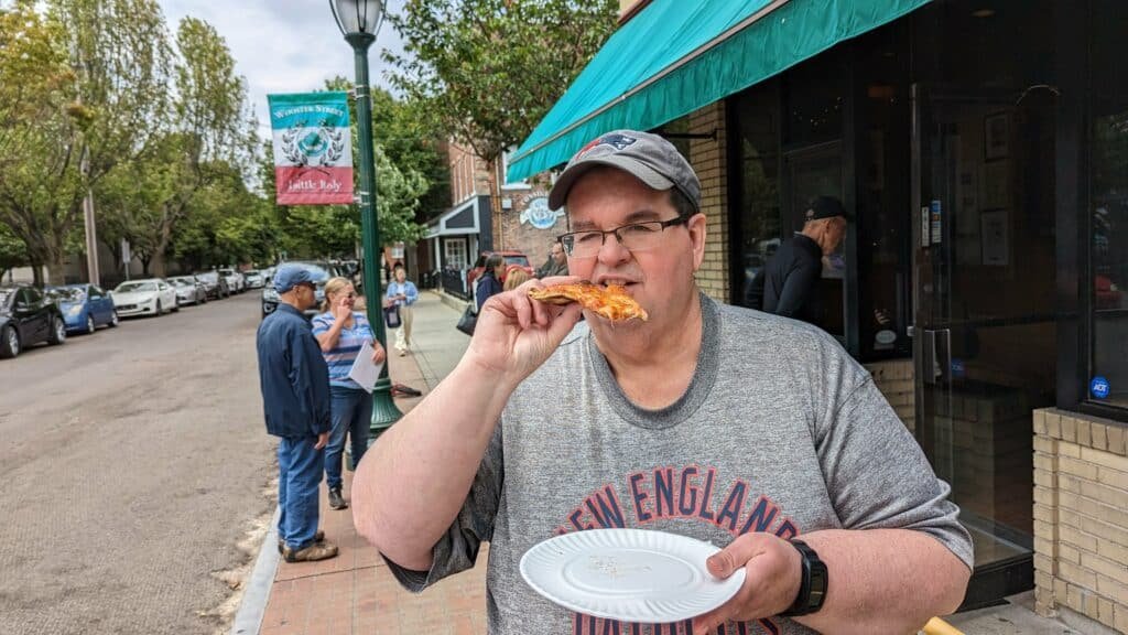photo of Bobby Warren eating a pizza in front of Frank Pepe Pizzeria Napoletana for a Frank Pepe pizza review