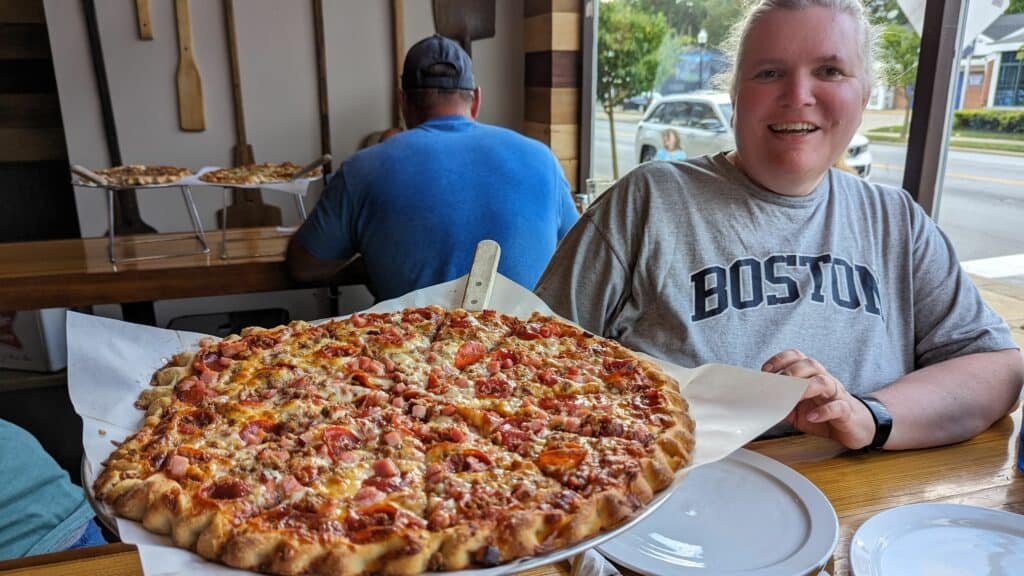 Photo of meat loves pizza with Wendi Warren sitting in the background